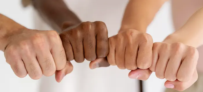  hands of different skin tones, symbolizing the issue of discrimination based on race, age, gender, or religion.